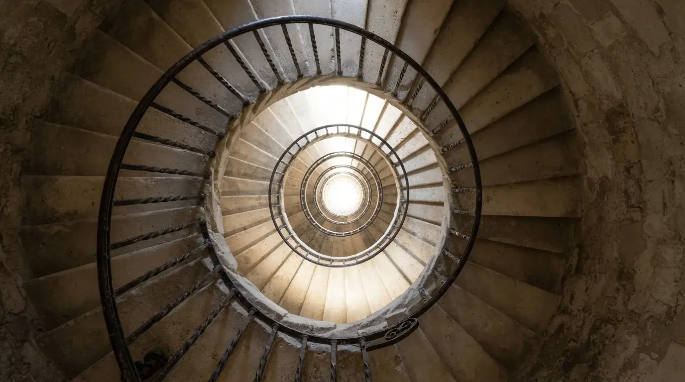 Trepte de piatră ale unei scări în spirală, văzute de sus, cu lumină naturală.